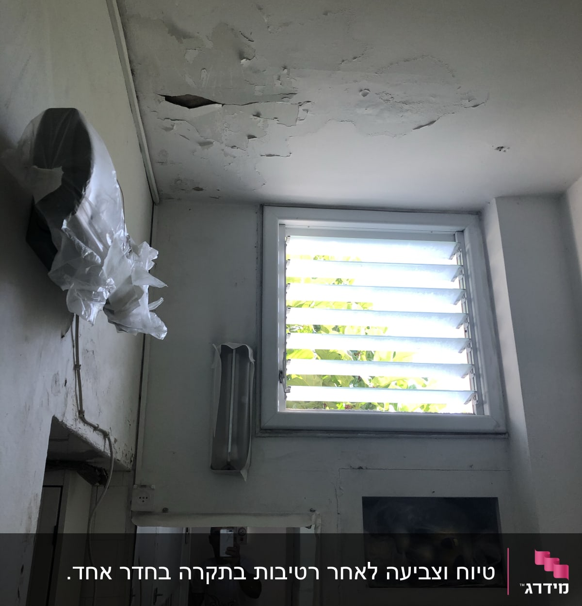 תקרה מתקלפת עם סימני רטיבות ליד חלון